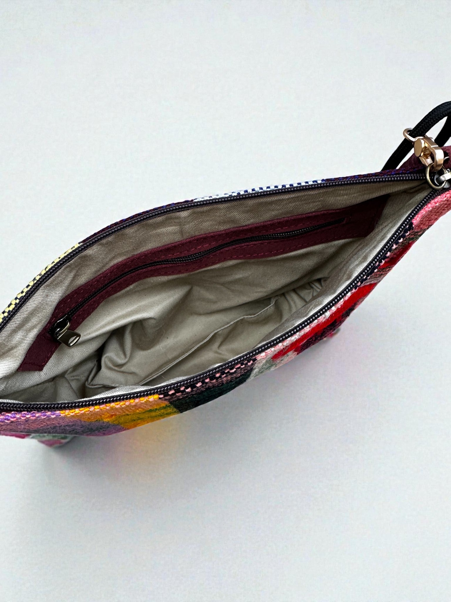 Ein Blick von oben auf die LEY! Tasche - OCULIA CLUTCH von LEY!, einer handgefertigten Umhängetasche mit buntem Vintage-Stoff-Patchwork, hellgrauem Innenfutter und Reißverschluss-Innentasche.