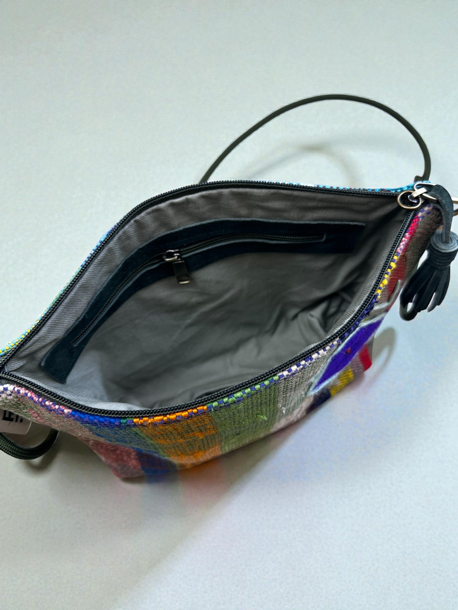 Freie Sicht auf die LEY! Tasche - OCULIA CLUTCH von LEY!, eine bunte, handgefertigte Umhängetasche mit Pailletten und schwarzem Riemen, mit grauem Innenfutter und Reißverschluss-Innentasche von Vintage-Stoff.