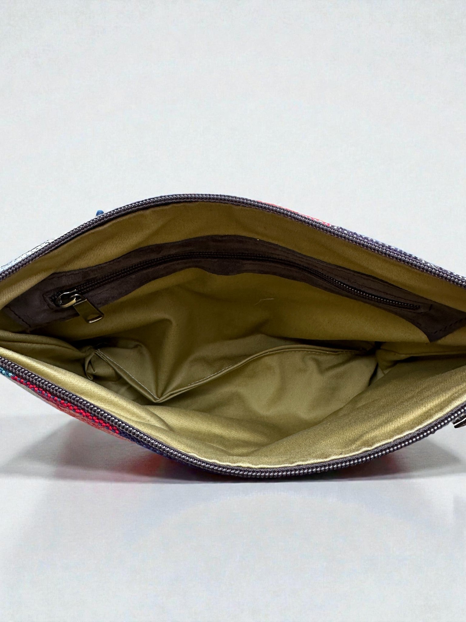 Eine Nahaufnahme der LEY! Tasche - OCULIA CLUTCH von LEY! zeigt ihr hellbraunes Innenfutter und die Innentasche mit Reißverschluss - ideal für alle, die Vintage-Stoff in einer handgefertigten Umhängetasche lieben.