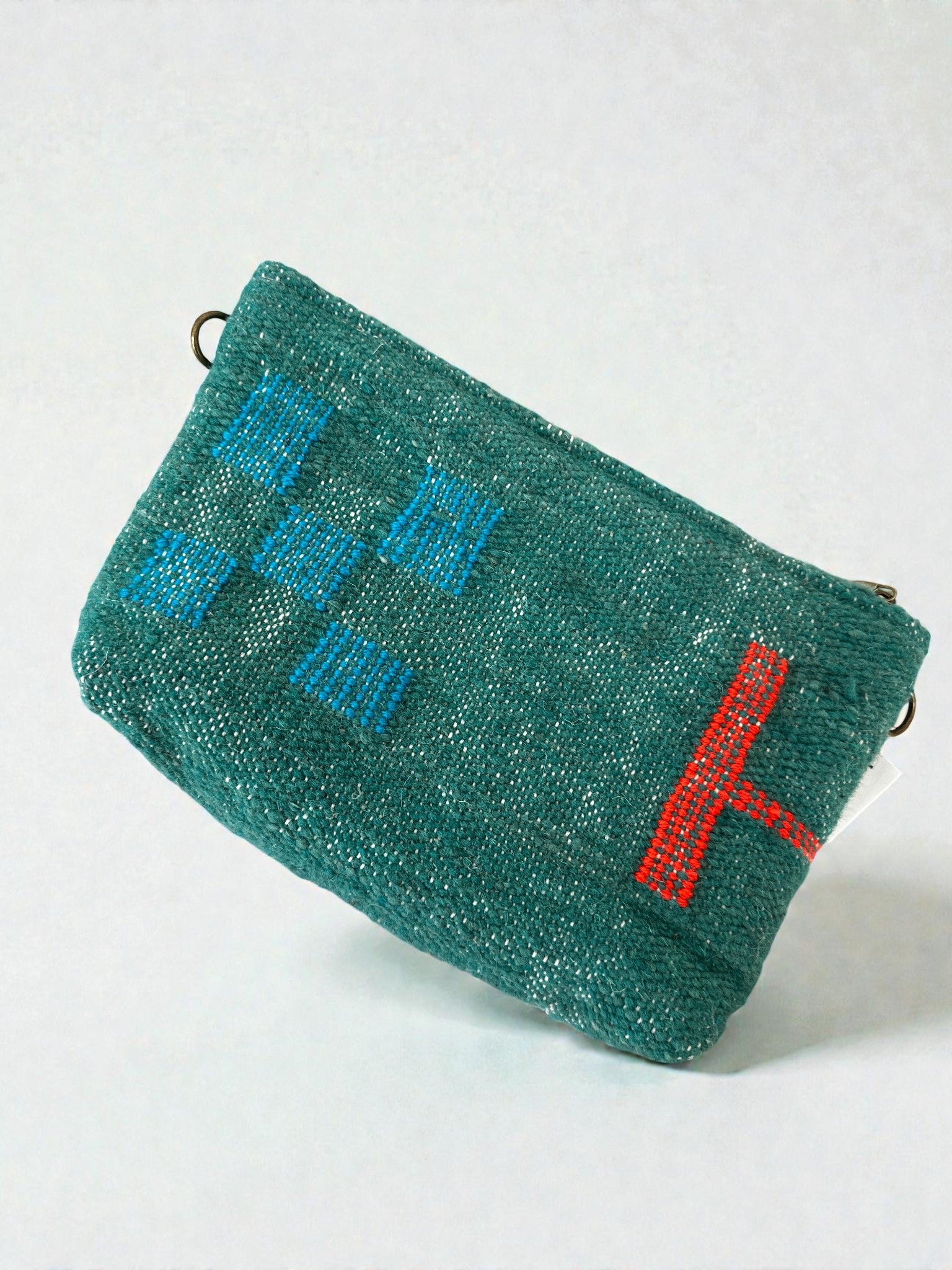 Die LEY! Tasche - Colorful Line (20 x 30 cm) ist eine strukturierte grüne Schurwolle-Clutch mit blauen und roten gestickten geometrischen Mustern und einem lebhaften, von der Handarbeit Marrakesch inspirierten Linienmotiv auf hellem Grund.