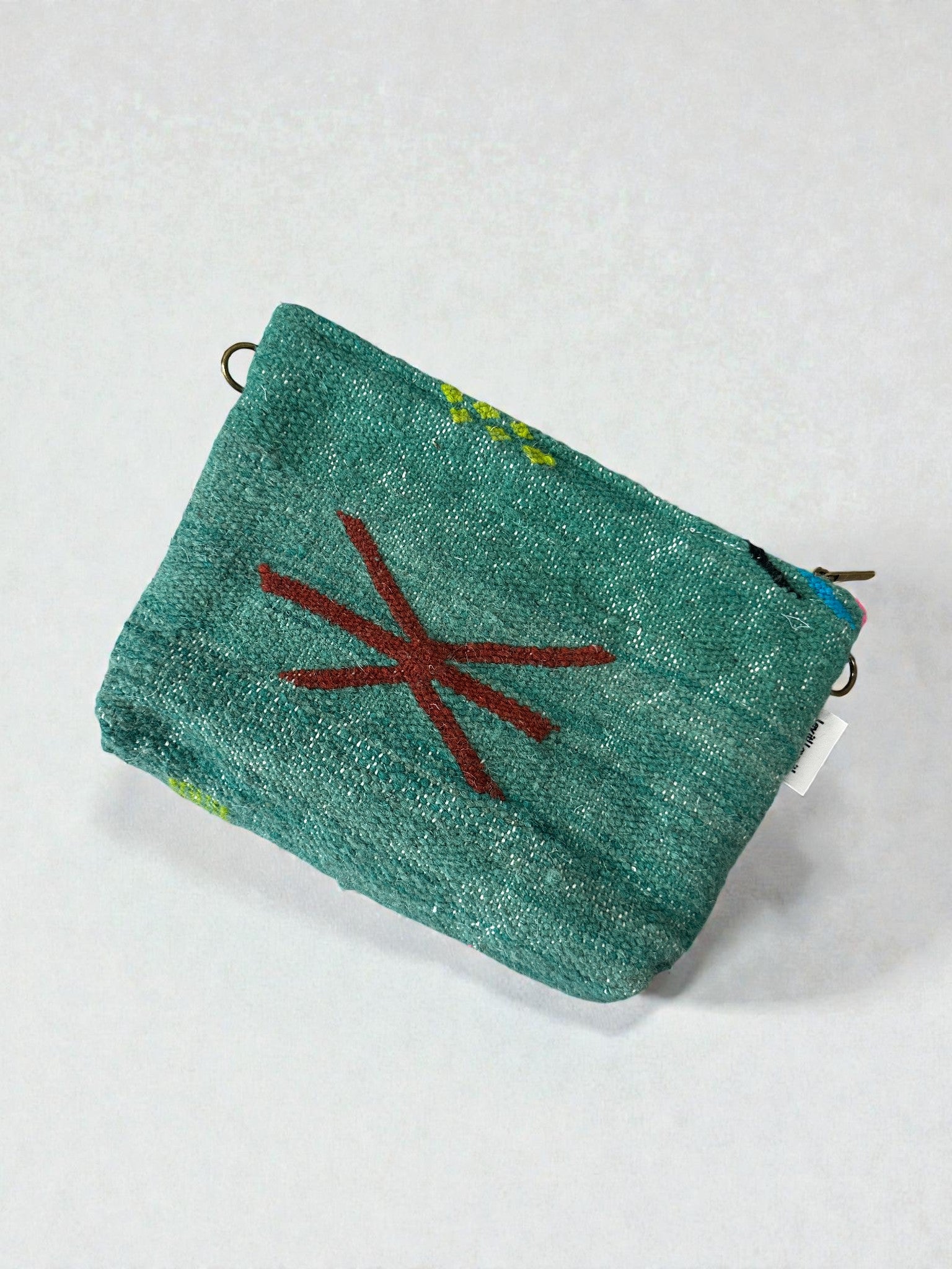 Die Tasche - Colorful Line - 20 x 30 cm von LEY! ist eine kleine, rechteckige, tealfarbene Stofftasche mit metallischem Glanz und einem einfachen, roten Sternchen-Symbol auf einem schlichten, weißen Hintergrund.