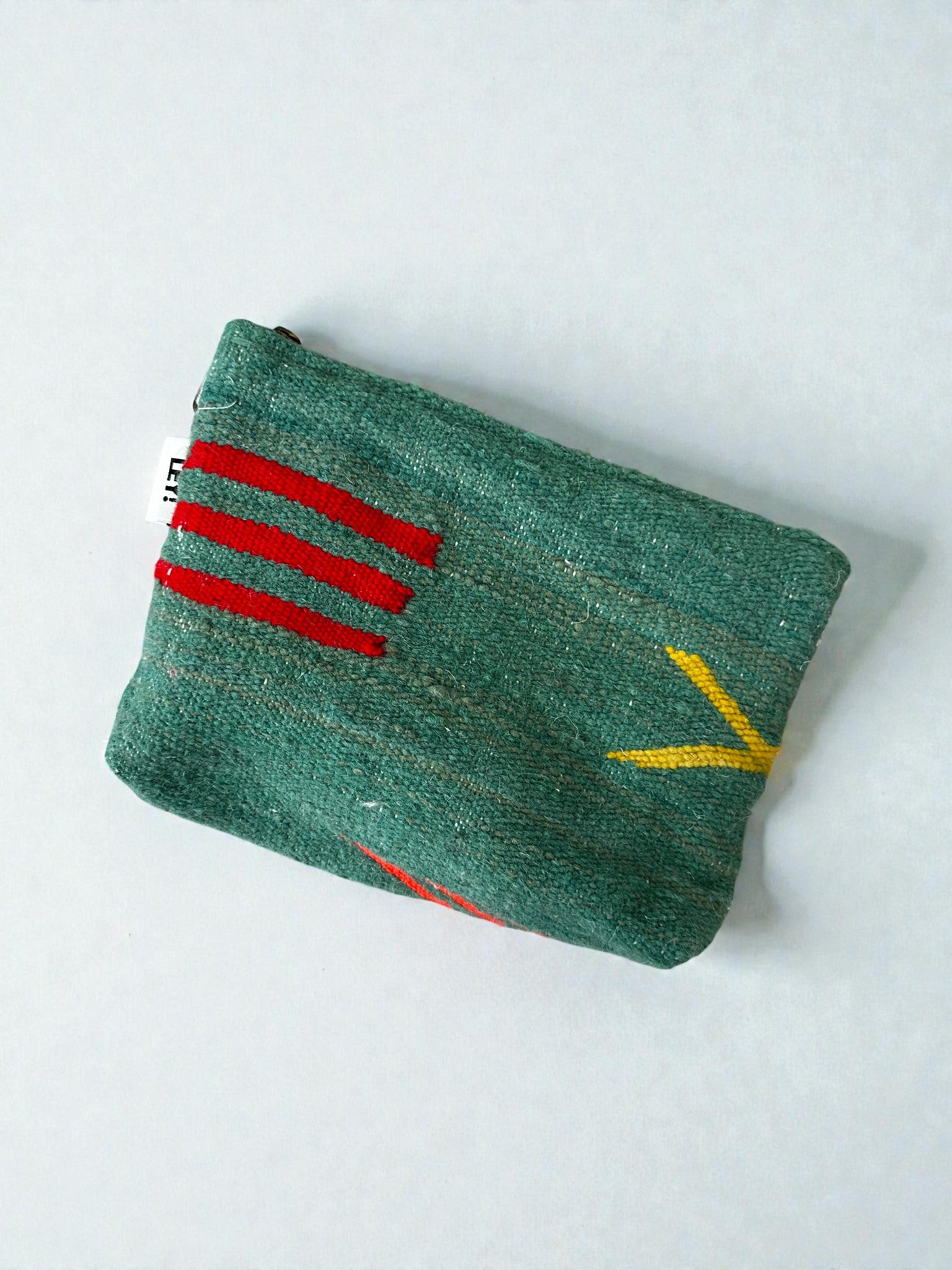 Die LEY! Tasche - Colorful Line (20 x 30 cm) ist eine kleine grüne Schurwolltasche mit roten und gelben Stickmustern, darunter drei rote Linien und ein gelbes pfeilartiges Detail, handgefertigt im Marrakesch-Stil und auf hellem Hintergrund.