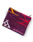 Die LEY! Tasche - Colorful Line - 15x20cm ist eine kleine, lila strukturierte Tasche mit Reißverschluss, die mit roten, gelben, weißen, rosa und blauen geometrischen Stickereien und einem seitlichen weißen Stoffanhänger versehen ist, inspiriert von Handarbeit Marrakesch.