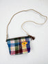 Die LEY! Tasche - OCULIA CLUTCH von LEY! ist eine handgefertigte Umhängetasche aus buntem Vintage-Stoff mit tanfarbenem Riemen, gesticktem gelben Auge vorne, orangefarbenen Wimpern, Reißverschluss und braunem Quasten-Detail.