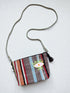 Die LEY! Tasche - OCULIA CLUTCH von LEY! ist eine kleine Crossbody-Tasche mit bunt gestreiftem Stoff, gesticktem Augenmotiv, Quasten-Reißverschluss und einem dünnen grauen Riemen.