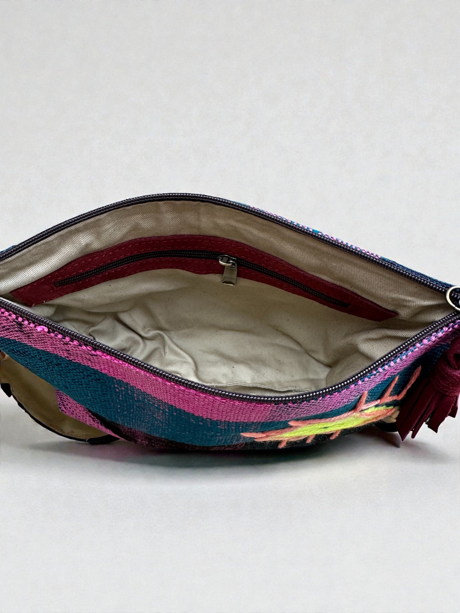 Die LEY! Tasche - OCULIA CLUTCH von LEY! ist eine farbenfrohe Reißverschlusstasche aus Vintage-Stoff, mit cremefarbenem Innenfutter und einer Innentasche mit Reißverschluss, offen auf einem unifarbenen Hintergrund abgebildet.