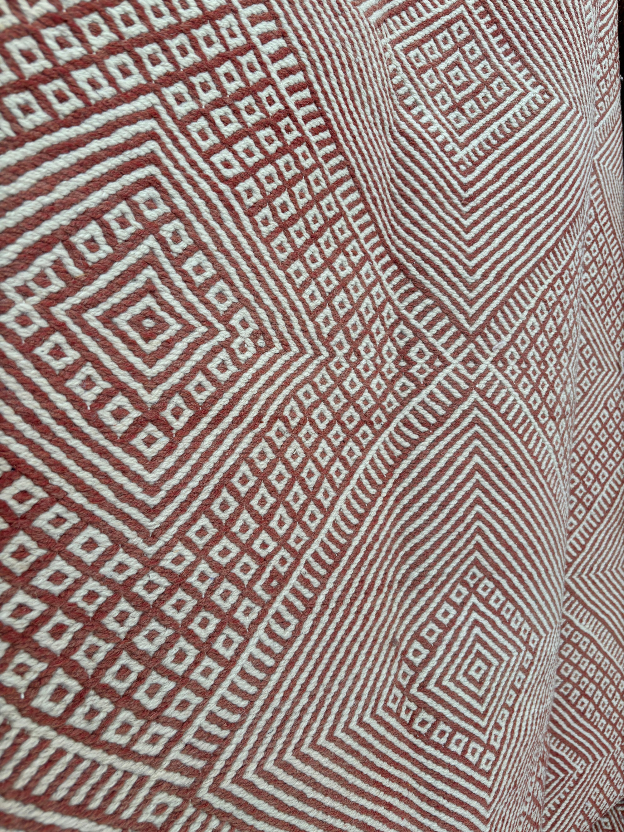 Nahaufnahme des LEY! Teppich "Sonia" (1,95 x 3,00), der ein kompliziertes geometrisches Muster mit weißen und rotbraunen konzentrischen Rauten und Quadraten zeigt, die einen eindrucksvollen dreidimensionalen visuellen Effekt erzeugen.