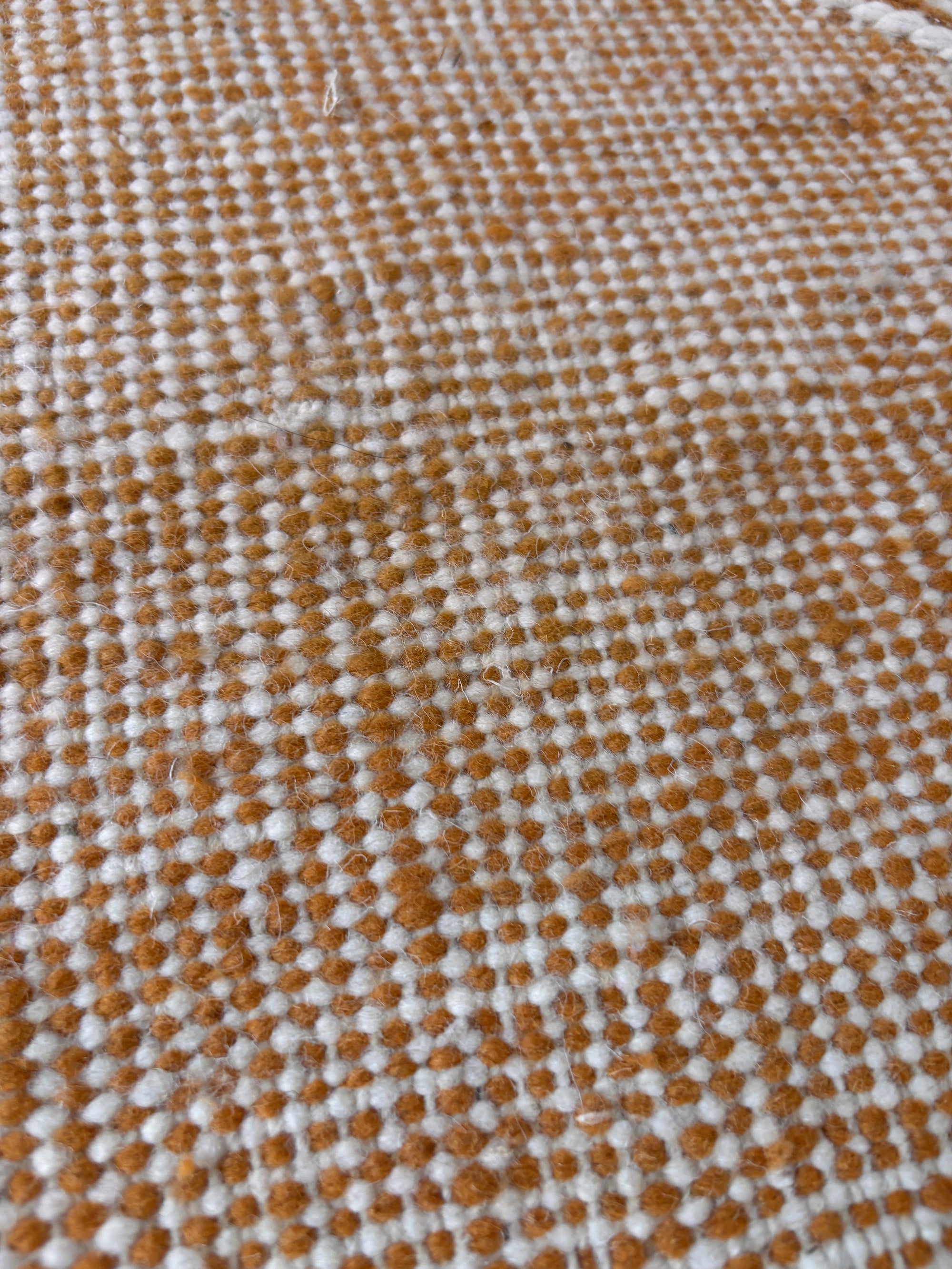 Nahaufnahme von LEY Teppich - Kastira - 1,50 x 2,55 von LEY!: ein gewebter Teppich, inspiriert vom handgeknüpften Kelim von Marokko, mit weicher Textur und braun-weiß gepunktetem Gittermuster, das einige lose Fasern aufweist.
