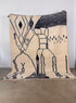 Der handgewebte Berber Teppich - Pippa von LEY! (2,10 x 2,90) aus Schurwolle mit abstraktem schwarzem Linienmuster steht an einer weißen Wand auf hellem Boden.
