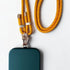 Eine tealfarbene Handyhülle ist an einer LEY! Handykette - Gelb - Orange mit Metallverschlüssen und Markenanhängern auf weißem Hintergrund.