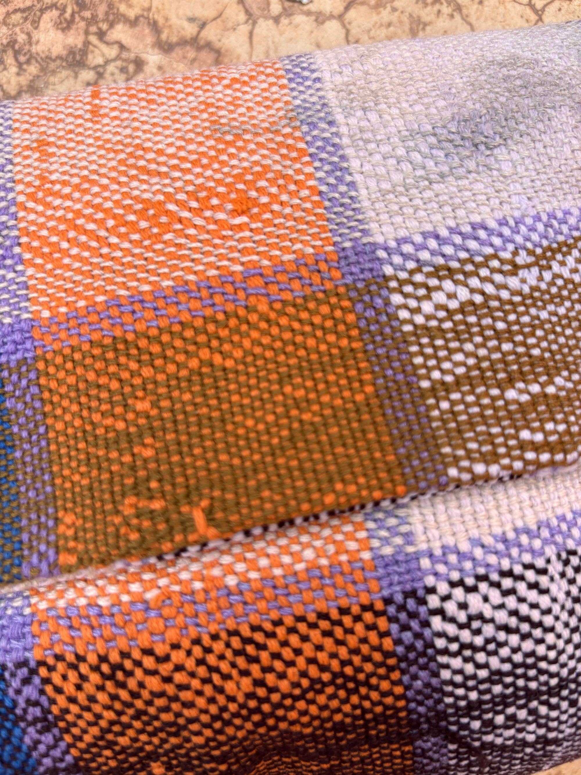 Eine Nahaufnahme der Vintage Clutch von LEY! zeigt ein kariertes Muster in Orange, Lila, Weiß und Braun mit strukturierter beiger Wolle - die perfekte Wahl für die Herstellung einer einzigartigen, handgefertigten Tasche aus hochwertigen Wollstoffen.