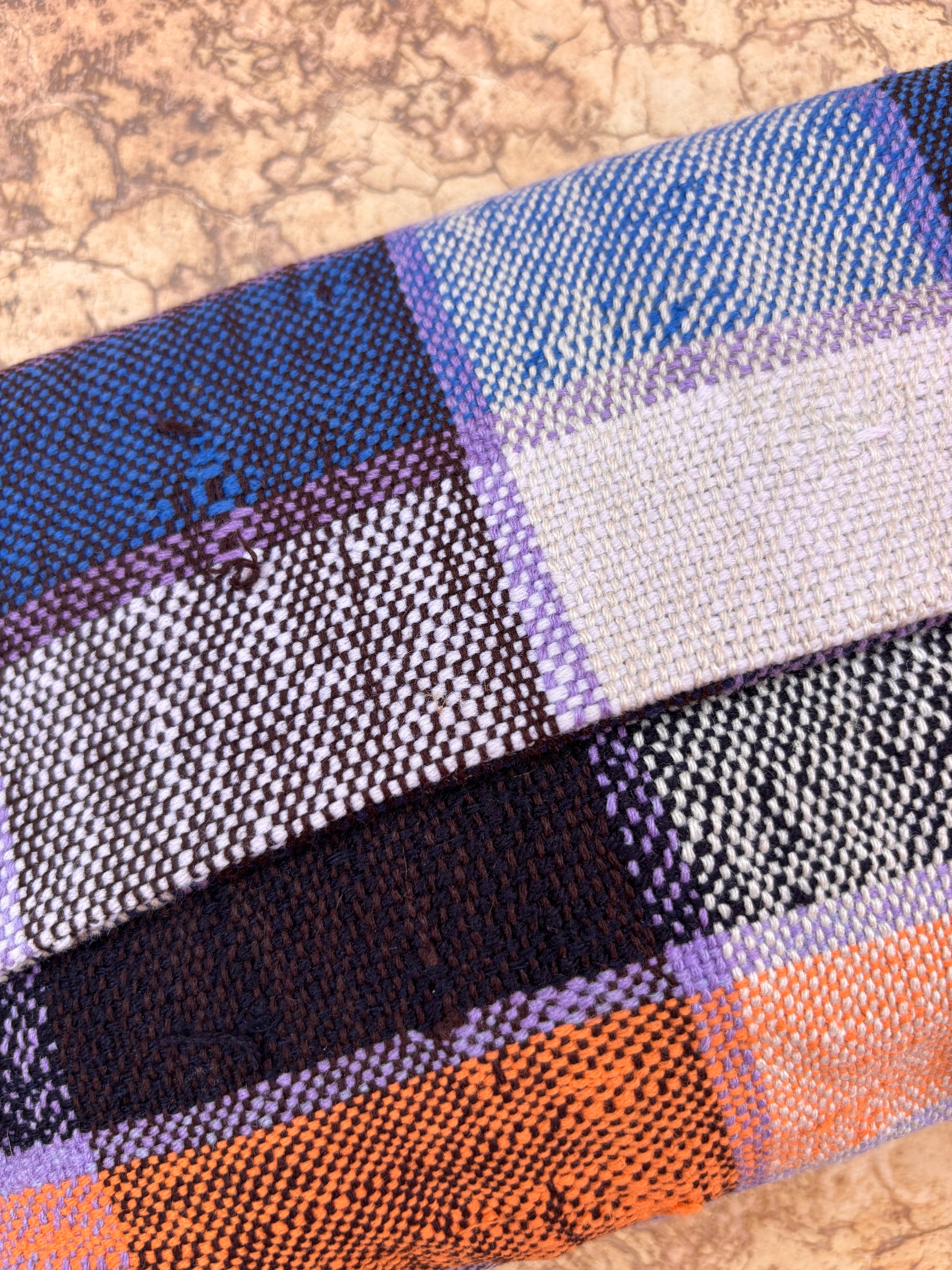 Eine Nahaufnahme des karierten Gewebes in Lila, Orange, Schwarz und Weiß auf Hellbraun - ideal für die Herstellung einer upgecycelten LEY! Vintage-Kupplung.
