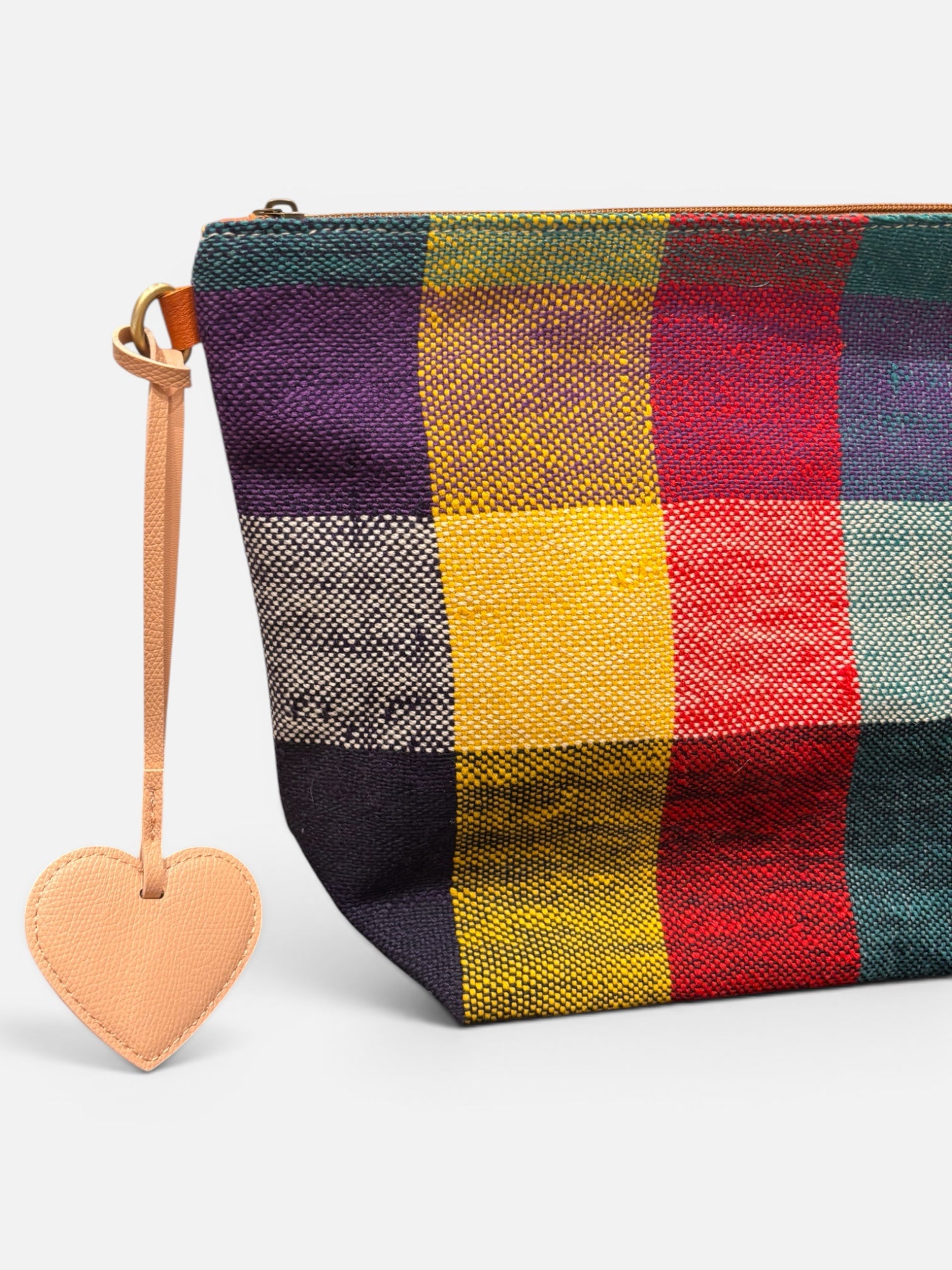 Nahaufnahme eines farbenfrohen, karierten Beutels mit dem LEY! Taschenanhänger – Love Loop – Apricot als Reißverschlussanhänger.