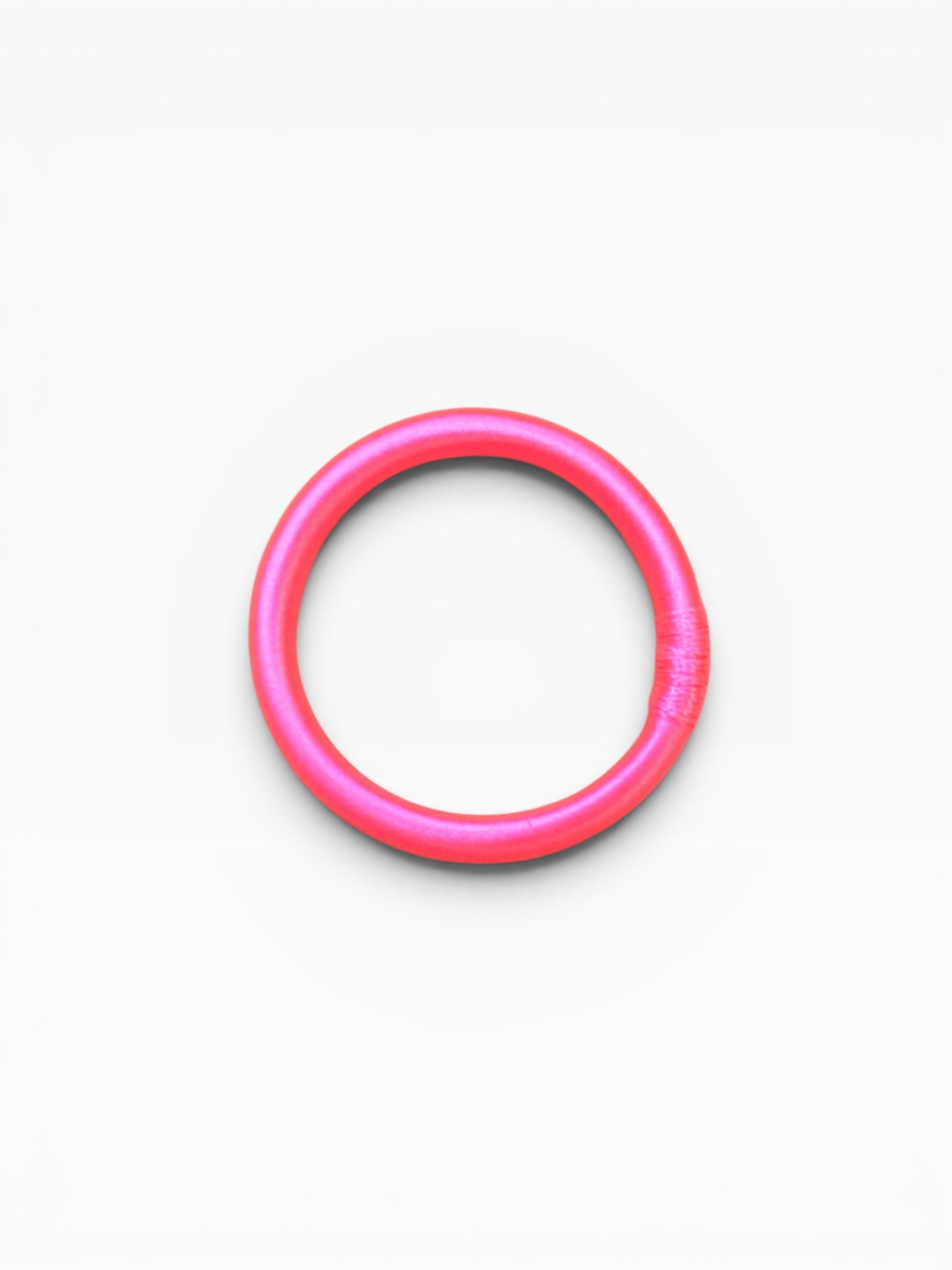 Ein neonpinker Armreif – „Minama“ von LEY! – ist in der Mitte eines schlichten weißen Hintergrunds abgebildet.
