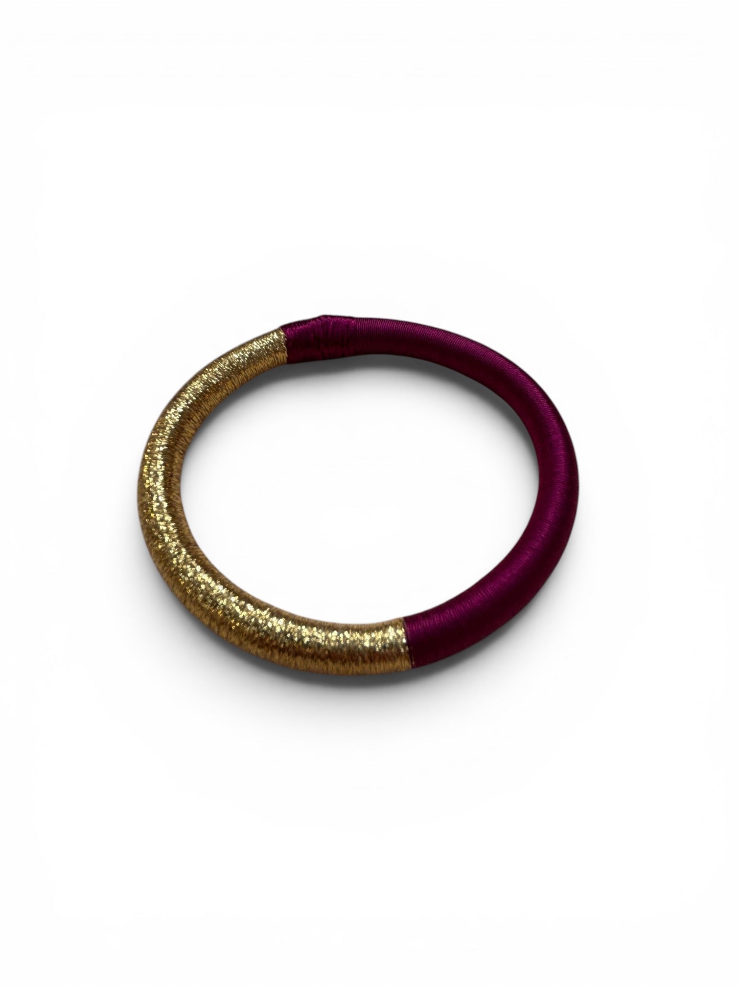 Handgefertigter LEY! Armreif „Mirama“ in Aubergine-Gold: Goldglitter und Fadenkunst auf weißem Hintergrund.
