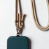 Eine grüne Handytasche mit der LEY! Handykette - Beige, mit beiger Flechtung und goldenen Verschlüssen, ruht auf einer weißen Oberfläche.