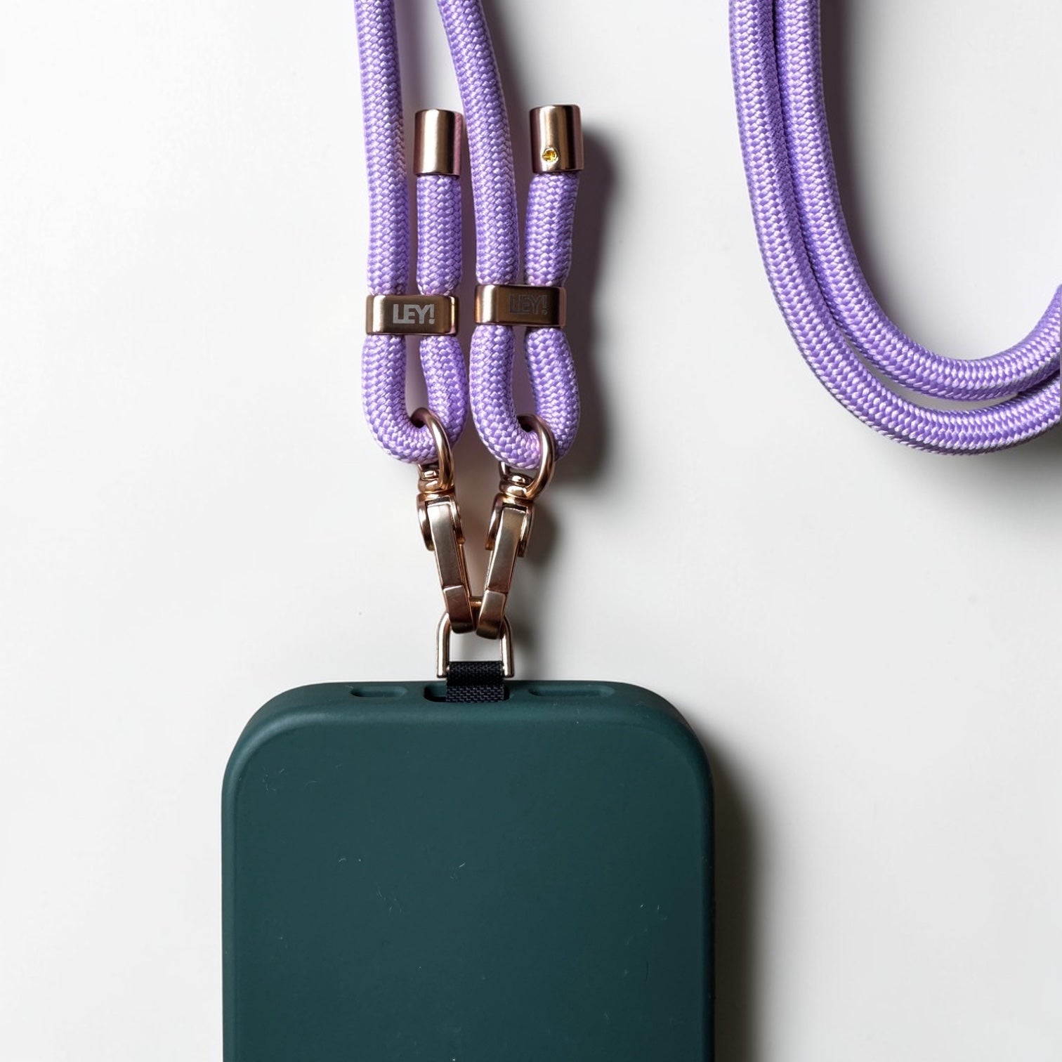 Eine dunkelgrüne Handyhülle ist an der LEY! Handykette - Lila, mit Metallclips und Markenanhängern auf einer weißen Oberfläche.